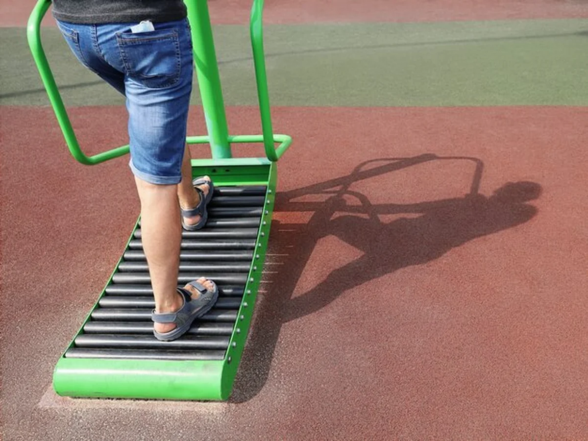 Nogi sportowca-amatora na bieżni ulicznej z cieniem na boisku sportowym