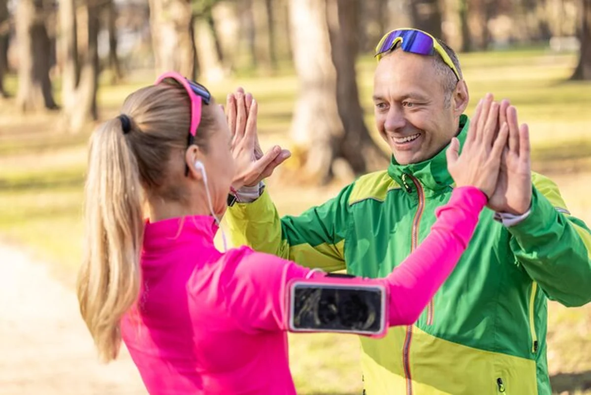 Dojrzały mężczyzna i młoda kobieta dają sobie piątkę po biegu