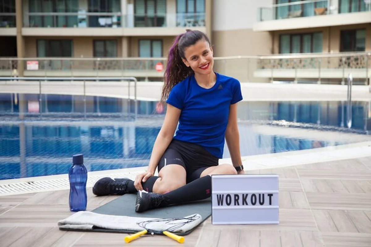 Młoda kaukaska kobieta ćwiczy na zewnątrz przy basenie podczas pandemii sportowej