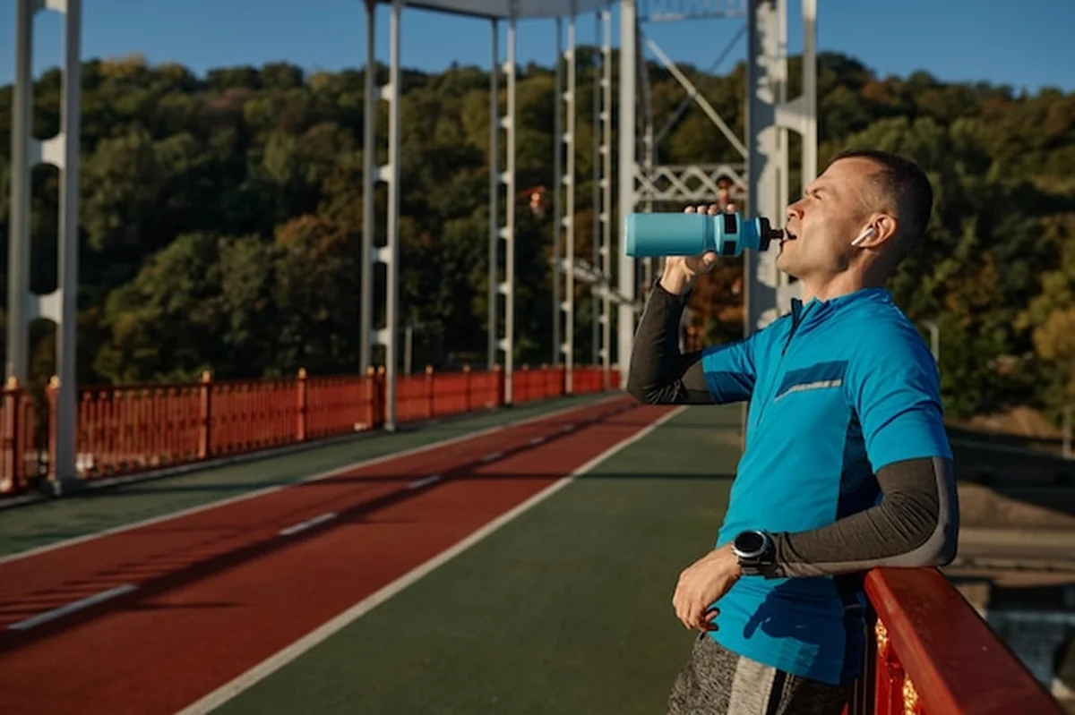 Zmęczony biegacz pijący wodę na moście miejskim podczas odpoczynku