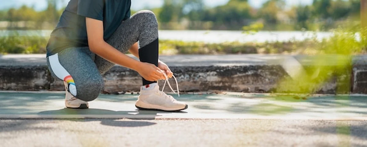 Kobieta biegaczka wiążąca sznurowadła w parku