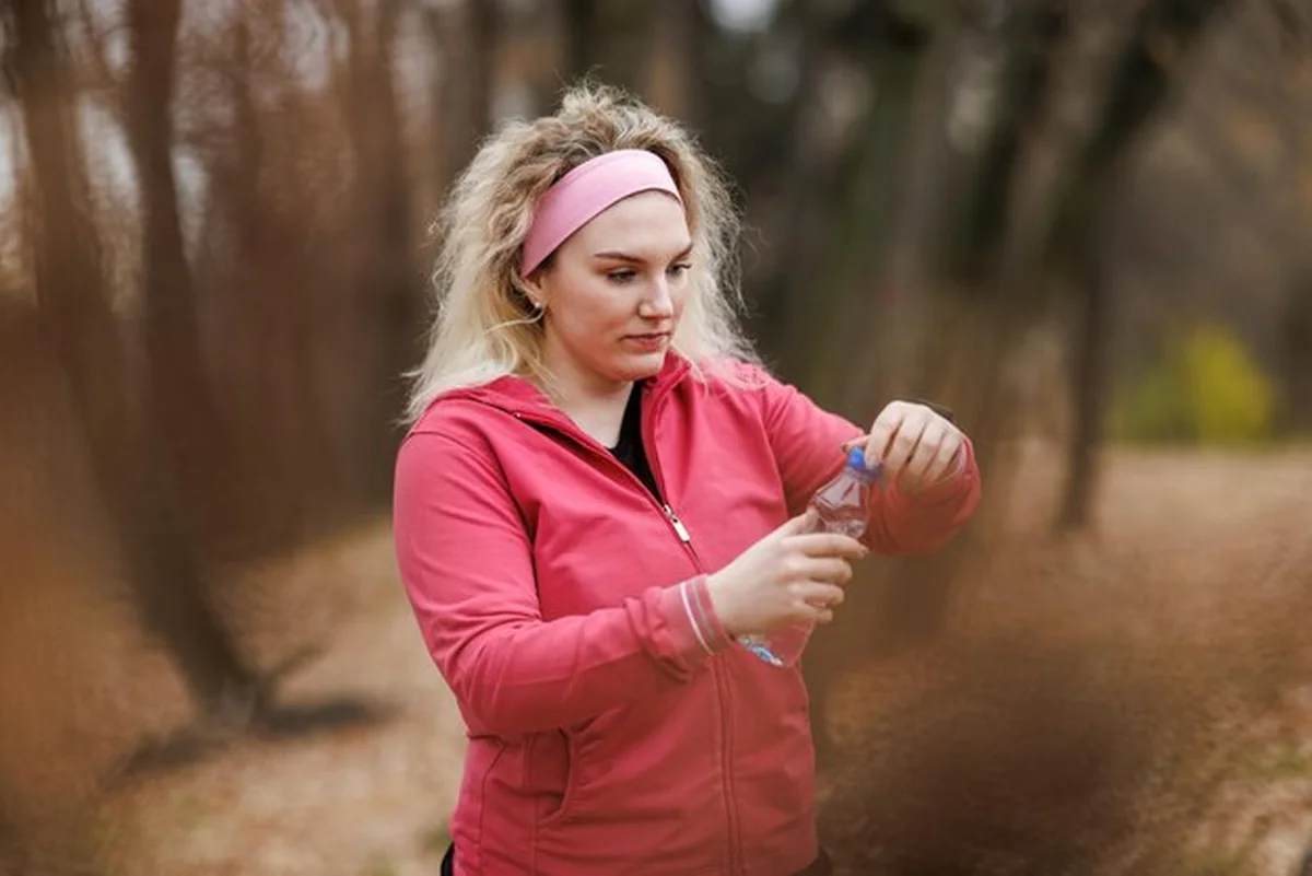 Kobieta trzymająca butelkę wody i odpoczywająca na świeżym powietrzu